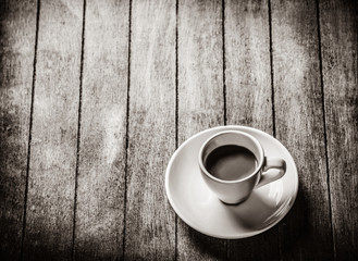 Little a cup of coffee on a wooden table. Image in white and black color style