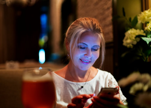 Pretty blonde woman looking at smartphone in cafe