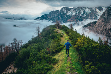 Tourist in blue jacket walking on green mountains ridge. Julian Alps, Slovenia. Vrsic Pass - obrazy, fototapety, plakaty