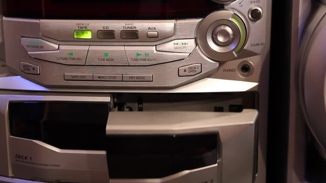 The hand inserts tape into an audio player and regulates loudness