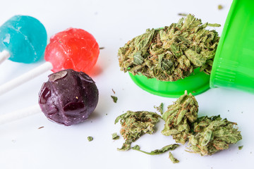 Open bottle of medicinal cannabis flower buds with marijuana infused candy lollipops