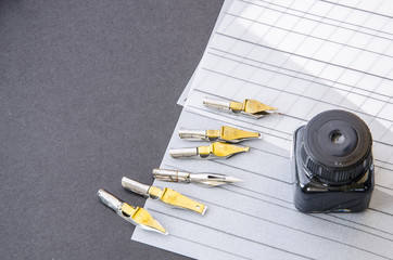 calligraphy pen tips , flat tipped nib, ink and practice sheets on the table