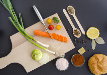 Fototapeta na wymiar Fresh ingredients for healthy cooking on dark background and cutting board