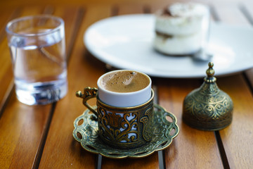 Turkish coffee with a glass of water and traditional copper serving set