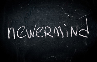 word nevermind written in white chalk on a school blackboard