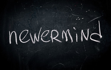 Fototapeta premium word nevermind written in white chalk on a school blackboard
