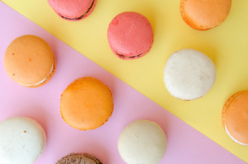 assortment of macarons on yellow - pink background divided diagonally into two triangles