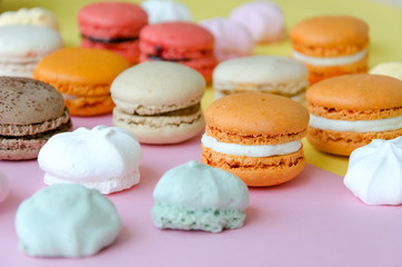 Assortment of macarons and meringues on pink background