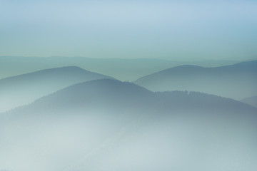 Misty mountain hills landscape. View of  layers of mountains and haze in the valleys. The effect of color tinting.