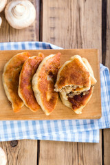 Fried pies with mushrooms, homemade cakes, wooden background, rustic retro style
