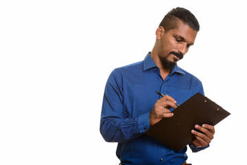 Young Indian businessman writing report on clipboard