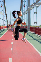 Obraz premium Young woman athlete in sport apparel jumping during the workout. Empty space