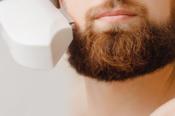 Male depilation laser hair removal beard and mustache procedure treatment in salon.