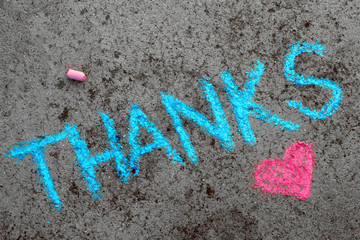 Colorful chalk drawing on asphalt: Blue word THANKS and small pink heart