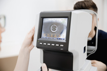 Female hand doctor holds monitor of ophthalmological device with indicators eye pressure and...