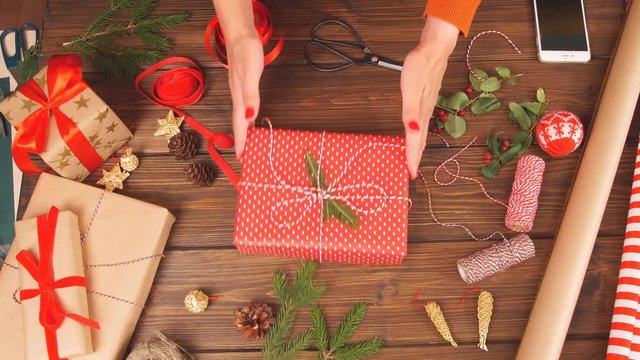 Holiday decor concept. Woman's hands tying christmas holiday handmade present in craft paper with twine ribbon. Making bow at xmas gift box. Creative hobby.