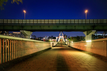 Empty foot bridge under expressway in city at night