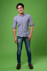 Young handsome Filipino man against green background