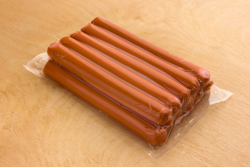 Sausages vacuum packed on a wooden surface. A bundle of sausages from the store on a wooden table.