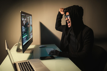Indian angry screaming young man in headset with pc computer playing game at home and streaming...