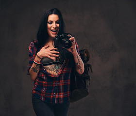 Seductive tattooed hipster girl wearing a red unbuttoned checked shirt posing a camera.