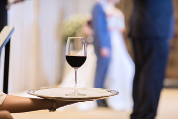 Waiter is carring plate with red Wine glasses. glasses. Wine glasses. Waitress holding a dish of champagne and wine glasses at festive event, party or wedding reception