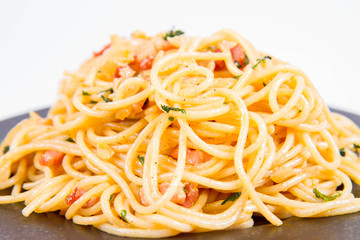 Spaghetti Carbonara with some parsley on a black plate on a white background