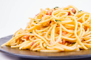 Spaghetti Carbonara with some parsley on a black plate on a white background