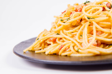 Spaghetti Carbonara with some parsley on a black plate on a white background