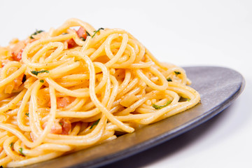 Spaghetti Carbonara with some parsley on a black plate on a white background