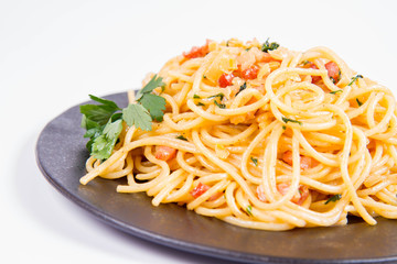 Spaghetti Carbonara with some parsley on a black plate on a white background