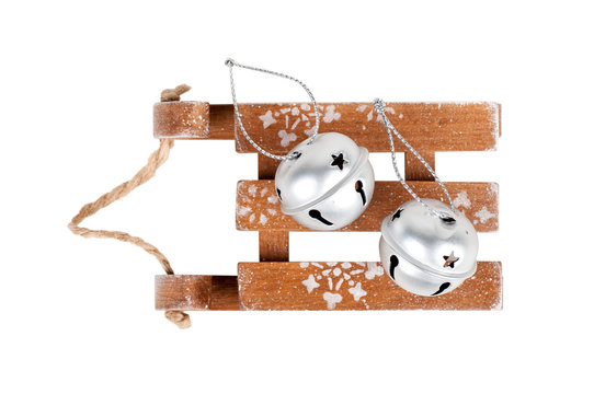 silver bells lie on a wooden sleigh, isolated