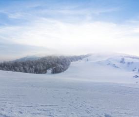 Fototapeta na wymiar snowbound winter plain with hills at the evening