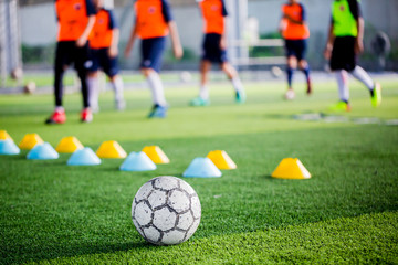 Soccer ball on green artificial turf with blurry of maker cones and player training. © Koonsiri