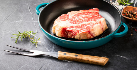 Raw Fresh Marbled Meat Beef Steak rosemary, spices on the grill pan. Black marble background.  Copy...