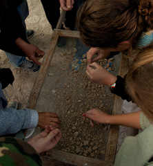Hands sifting stones at archaeological site