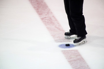 Fototapeta na wymiar black hockey puck and referee legs on ice rink. Winter sport.