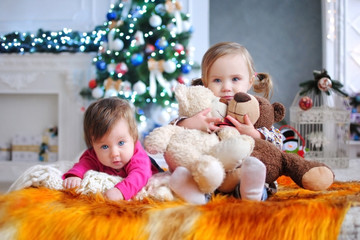 Дети ждут чудо в Новый год. С новым годом! Счастливого Рождества! Новогодняя елка с рождественскими игрушками. Две сестры на кровати.