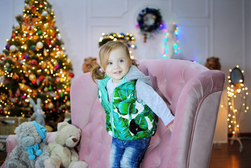 Ребенок ждет чуда в Новый год. С новым годом! Счастливого Рождества! Новогодняя елка с рождественскими игрушками. Девочка на диване.
