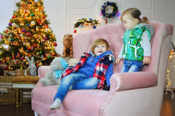 Дети ждут чудо в Новый год. С новым годом! Счастливого Рождества! Новогодняя елка с рождественскими игрушками. Брат с сестрой на диване.
