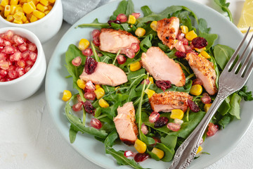Salad with grilled salmon, arugula, corn, pomegranate and cranberry sprinkled with lemon and olive oil.