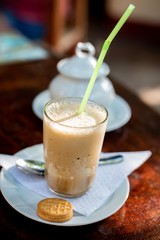 Glass of iced coffee with whipped cream on wooden background