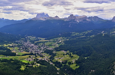 Cortina D Ampezzo aerial picture - city between green forest and mountains peaks.