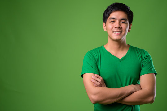 Young handsome Filipino man against green background