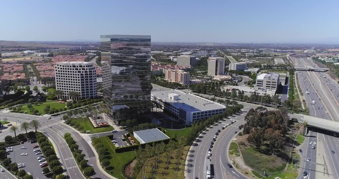 Aerial view of tall office buildings in corporate urban or city environment with highway in Southern California.