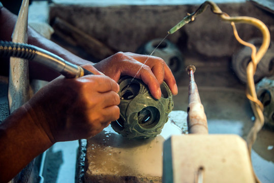 Chinese artisan carver hand carving a round jade puzzle ball also called a Generation Ball representing generations of a family