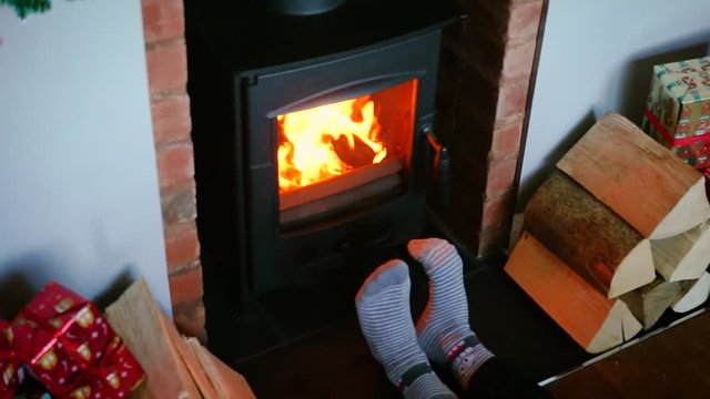 Feet in woollen socks by the christmas fireplace with presents
