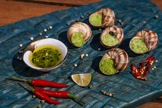 Bourgogne Escargot Snails with garlic herbs butter on the blue surface. Healthy food concept with copy space.
