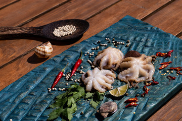 Fresh octopus in a blue plate with parsley and red pepper. On a wooden table.
