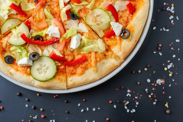 Close up of vegetarian pizza with vegetables on a dark background with copy space